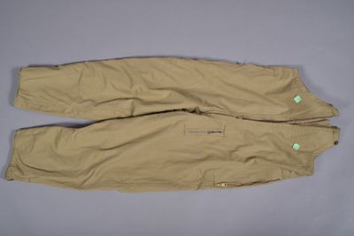 une photo d'un pantalon beige posé sur une surface grise