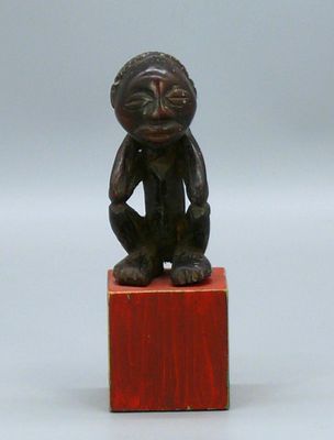 statue représentant un singe assis sur un bloc de bois