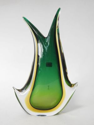 a green and yellow glass vase sitting on a white surface