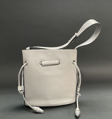 beige leather bucket bag with white cord handle and strap
