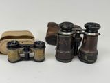 two old binoculars are sitting next to each other on a white surface