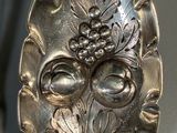 a silver spoon with a design on it hanging from a hook