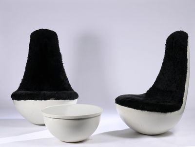 une paire de chaises noires et blanches et un bol posés sur une surface blanche