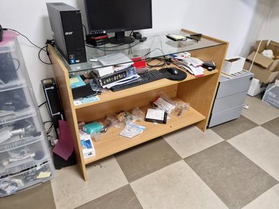 a desk with a computer monitor, keyboard, and other items on it