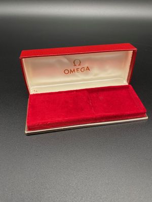 une montre Omega dans un coffret rouge posé sur une surface noire