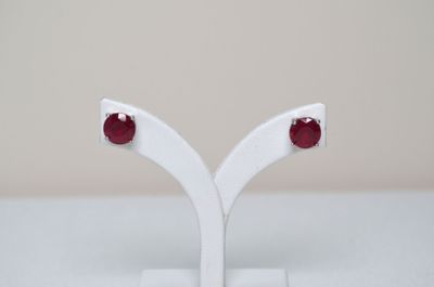 a close up of a pair of red stone earrings on a white stand