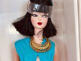 doll in a white box with a blue dress and gold accessories