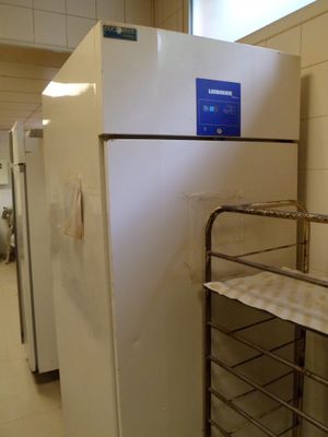 un réfrigérateur blanc sur lequel est apposée une étiquette bleue, dans une pièce