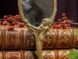 a mirror sitting on top of a stack of books next to a bunch of berries