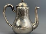 une théière en argent avec une anse, sur fond gris