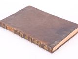 an old book sitting on top of a white table next to a white wall