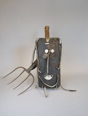 une sculpture métallique représentant une fourchette avec un visage dessus
