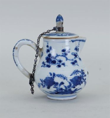 une théière bleue et blanche entourée d'une chaîne
