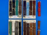 quatre montres différentes dans un coffret, avec des bracelets en cuir, sur fond bleu