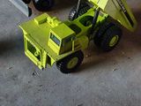 un camion-benne jaune et un camion-benne vert dans un garage