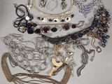 many different types of necklaces and bracelets laid out on a table