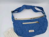 un sac à main bleu et des mitaines posés sur une table blanche