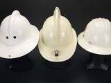 three white hard hats sitting on top of each other on a black surface