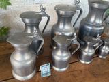 a lot of silver vases sitting on a wooden table