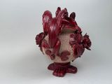 a vase with a red decoration on it on a white surface