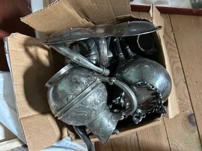 une boîte remplie d'objets en argent posée sur un plancher en bois