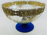 gold and blue glass bowl sitting on a blue pedestal