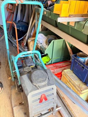 un diable bleu avec une poignée verte dans un garage