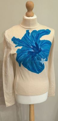 un pull crème orné de fleurs bleues, présenté sur un mannequin
