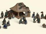 de nombreuses figurines représentant des personnes rassemblées autour d'une petite maison
