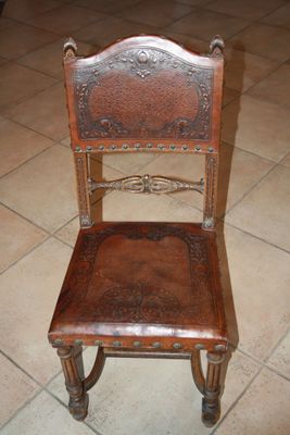 a wooden chair with a leather seat on a tile floor