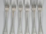 six forks are arranged in a row on a white surface