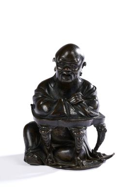 une photo représentant la statue d'un homme assis sur un tabouret