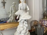 a statue of a woman sitting on top of a table next to a mirror