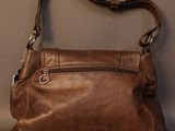 brown leather purse with zippers and a metal handle on a gray surface