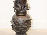 un vase en bronze orné d'un dragon, posé sur une table