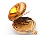 a gold pocket watch sitting on a white surface