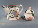 a small teapot next to a smaller teapot on a table