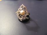 a pearl and diamond ring sitting on a black surface