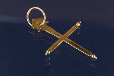 une clé dorée ornée d'une croix, posée sur une surface noire