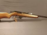 un fusil au canon en bois posé sur un support, sur fond blanc