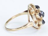 a close up of a gold ring with black stones on it