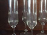 several empty wine glasses are lined up on a wooden shelf