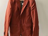 un blazer orange suspendu à un cintre accroché au mur