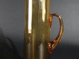 a yellow glass pitcher with a handle on a black table