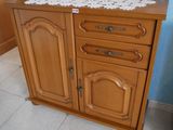une armoire en bois surmontée d'un napperon blanc