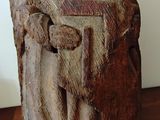 statue d'un homme assis sur une table en bois, avec un mur blanc en arrière-plan