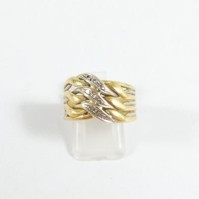gros plan d'une bague en or et en argent sur une surface blanche