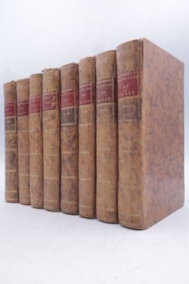 several old books are lined up in a row on a white surface