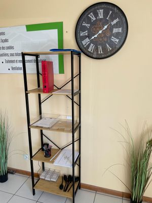 une horloge accrochée au mur au-dessus d'une étagère