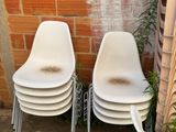 three white chairs sitting next to each other in front of a brick wall
